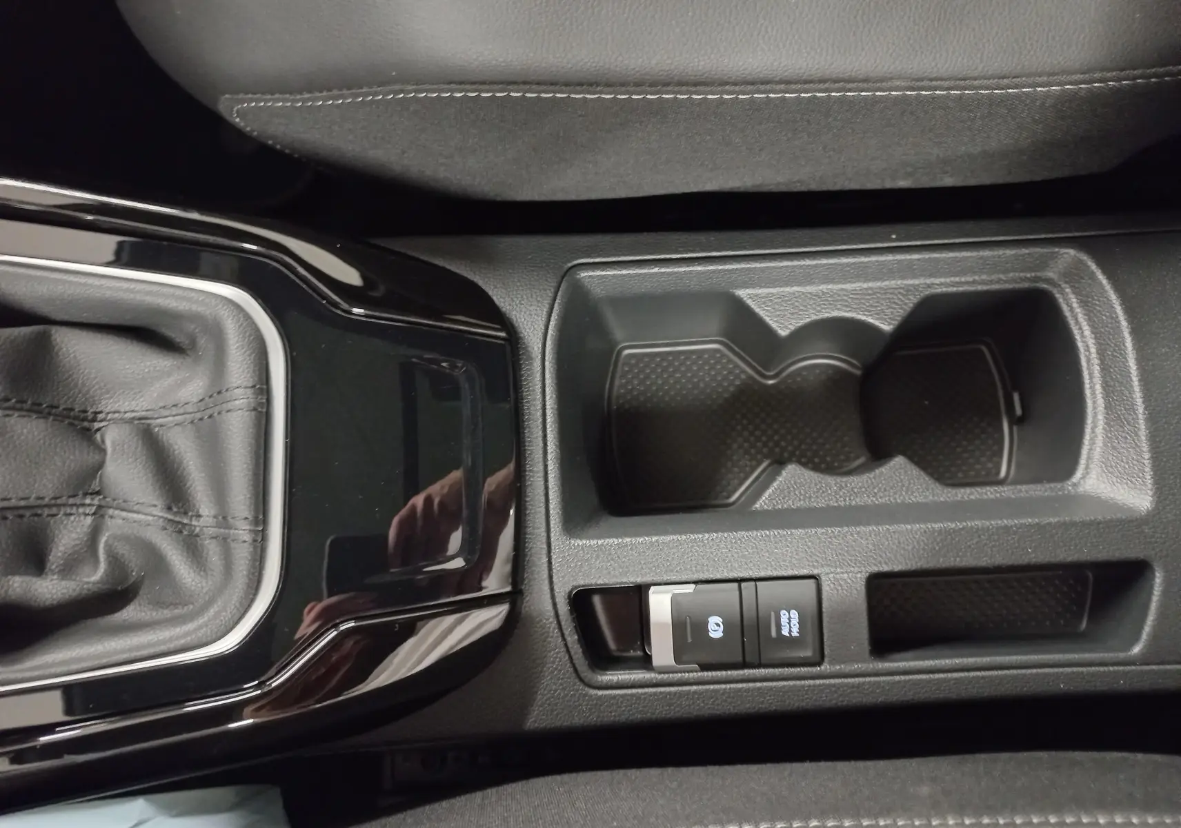 Gros plan sur la console centrale noire du Volkswagen T-Roc 2025, avec levier de vitesses et porte-gobelets.