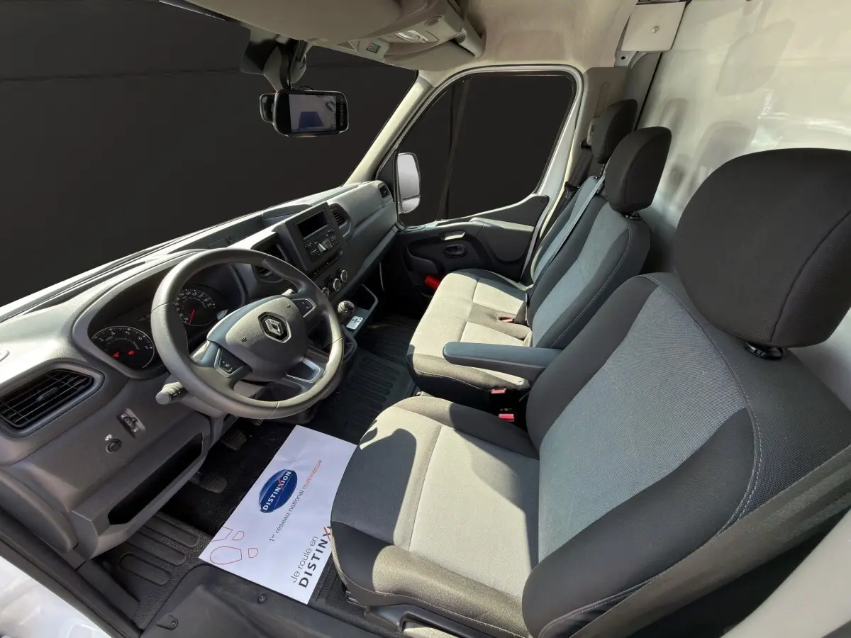 Vue intérieure côté conducteur du Renault Master 2024, sièges gris et tableau de bord noir avec volant multifonction.