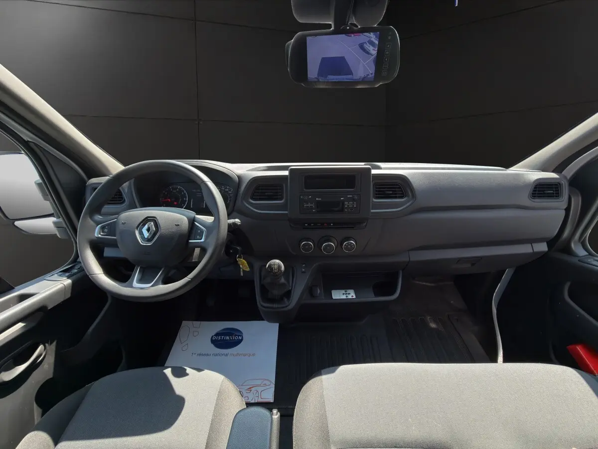 Vue intérieure avant du Renault Master 2024, tableau de bord gris avec volant, boîte manuelle et écran de rétrovision.