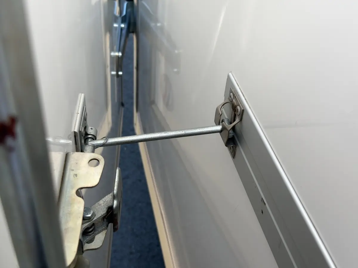 Gros plan sur le mécanisme d’ouverture de la porte latérale d’un Renault Master blanc, vue rapprochée côté droit.