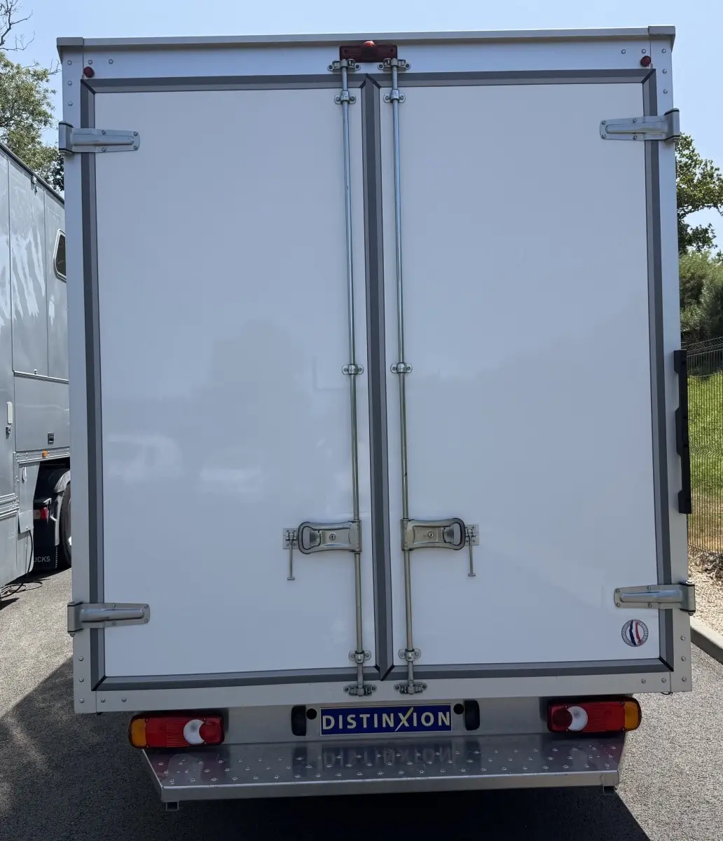 Vue arrière d’un utilitaire Renault Master blanc avec caisse fermée et double portes verrouillées, immatriculé DISTINXION.