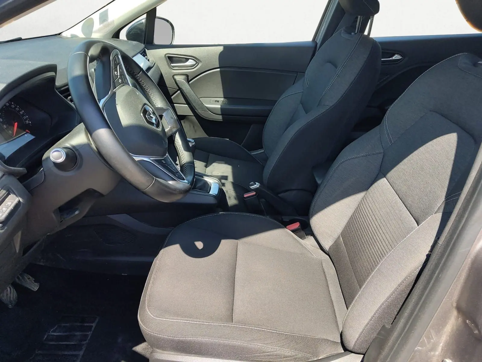 Vue intérieure côté conducteur du Renault Captur gris Cassiopée 2021, montrant sièges tissu et volant multifonction.