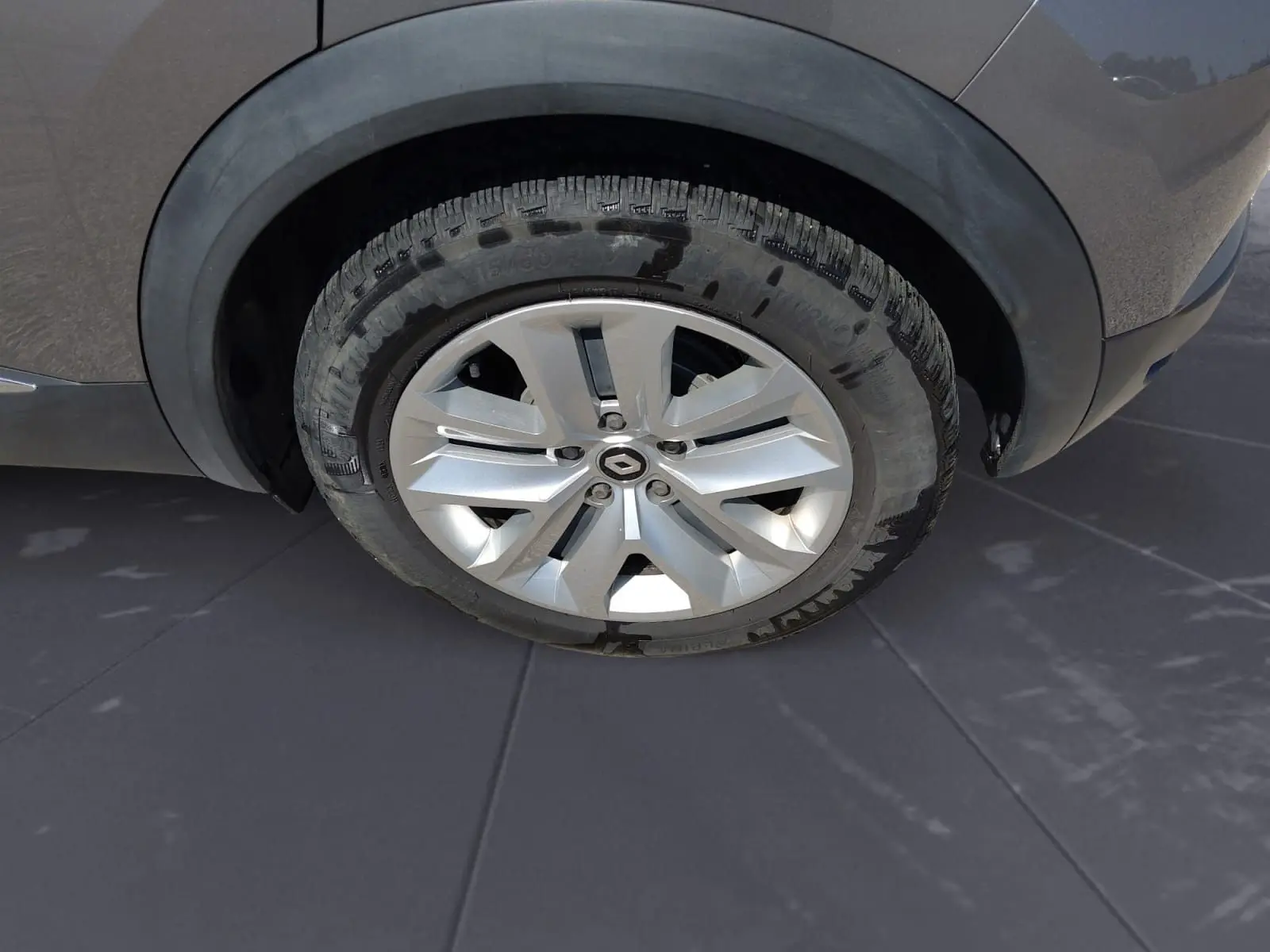 Gros plan sur la roue avant droite d’un Renault Captur gris Cassiopée, mettant en valeur la jante alliage et le pneu.