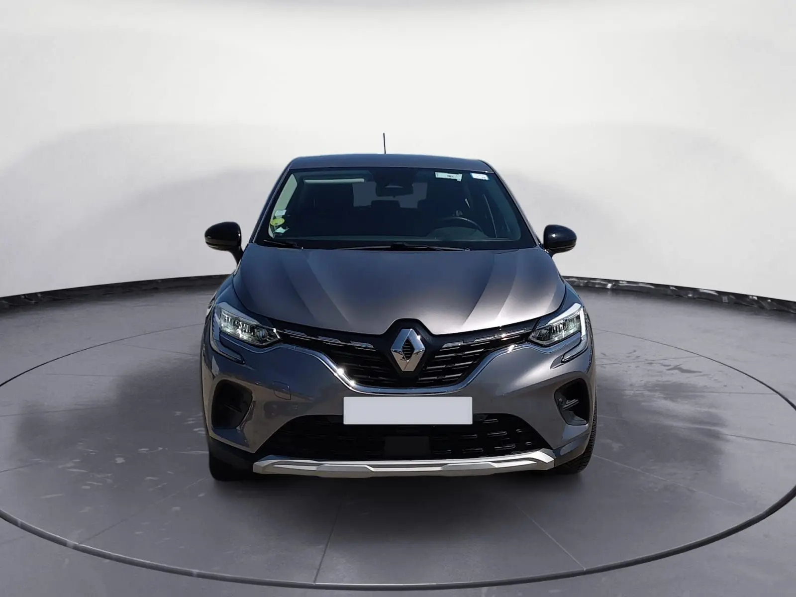 Vue de face du Renault Captur 1.5 Blue dCi 115 Business gris Cassiopée avec calandre chromée et phares LED allumés.