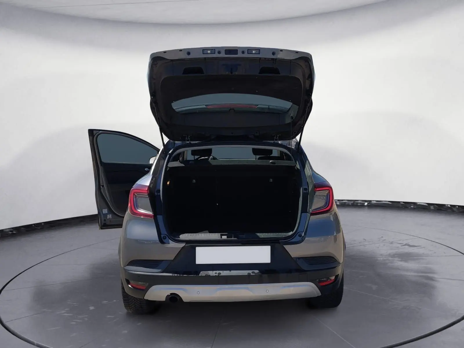 Vue arrière d'un Renault Captur gris Cassiopée 2021 avec coffre et porte côté gauche ouverts, mettant en valeur l'espace de chargement.