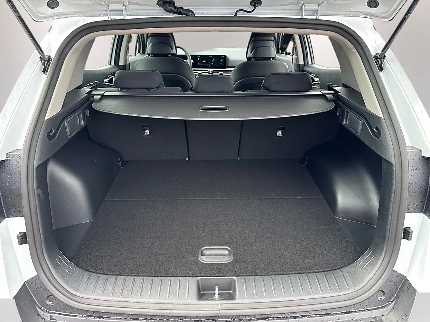 Coffre ouvert vu de l'arrière d'un KIA Sportage blanc 2026 avec banquette arrière et tablette cache-bagages.