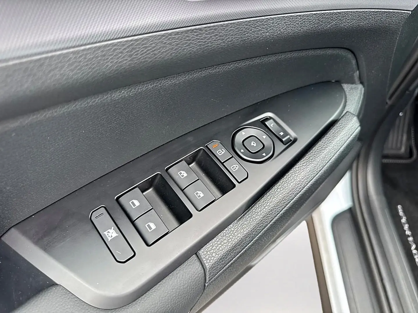 Vue rapprochée de la porte avant gauche du Kia Sportage blanc, avec commandes électriques des vitres et rétroviseurs.