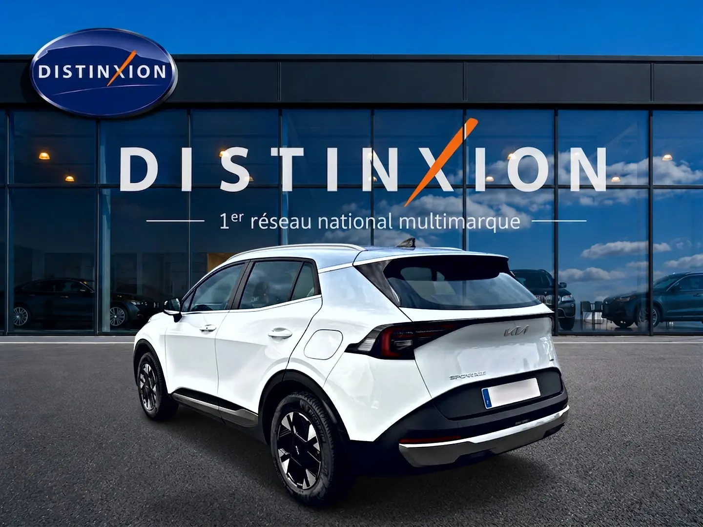 Vue 3/4 arrière droite d'un KIA SPORTAGE blanc 2026 hybride, avec jantes alu noires et toit contrasté noir.