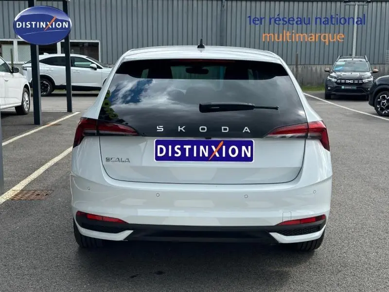 Vue arrière d'une Skoda Scala blanc cristal 2025 avec feux arrière LED et lunette arrière teintée sur parking.