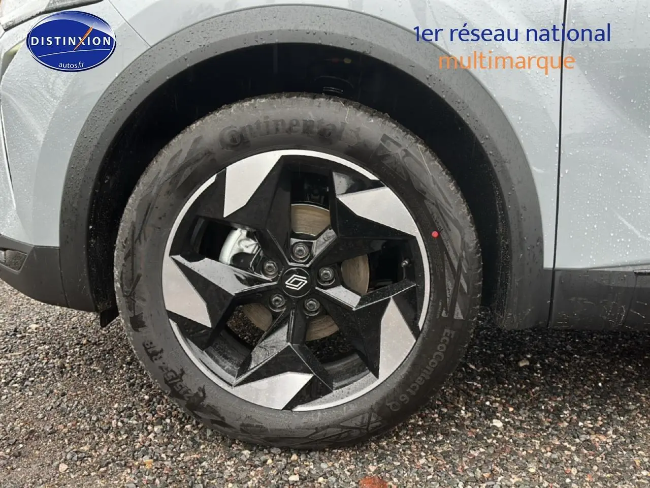 Gros plan sur la roue avant gauche du Renault Captur gris rafale avec jante alu bicolore au design géométrique.