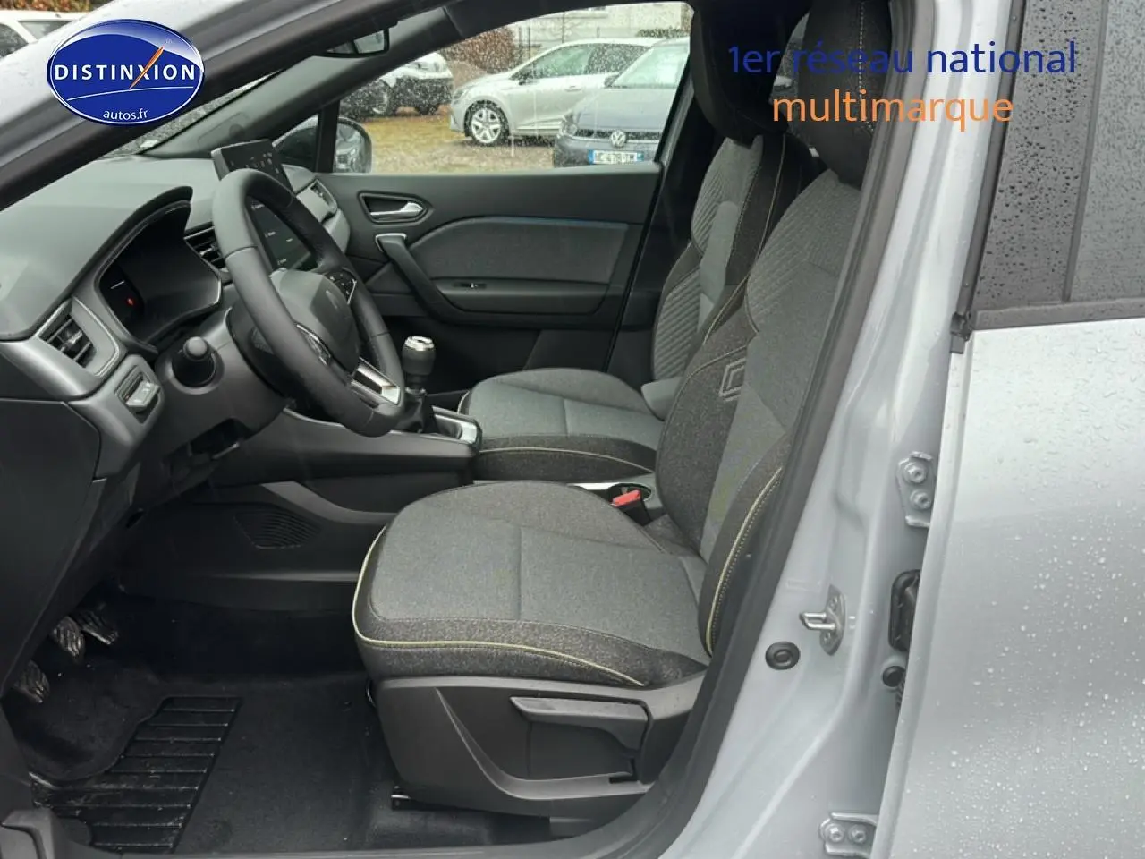Intérieur côté conducteur du Renault Captur gris rafale 2026, sièges tissu gris et volant multifonction.