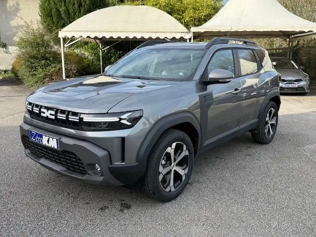 Vue 3/4 avant droite du Dacia Duster 1.8 Hybrid 155 Journey gris schiste avec jantes bi-ton et sellerie spécifique.