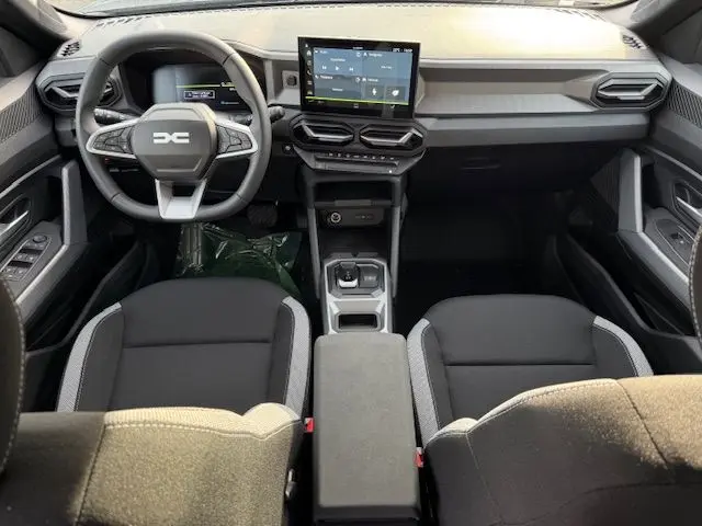 Vue intérieure frontale du tableau de bord et des sièges noirs avec sellerie spécifique Journey du Dacia Duster 2026.