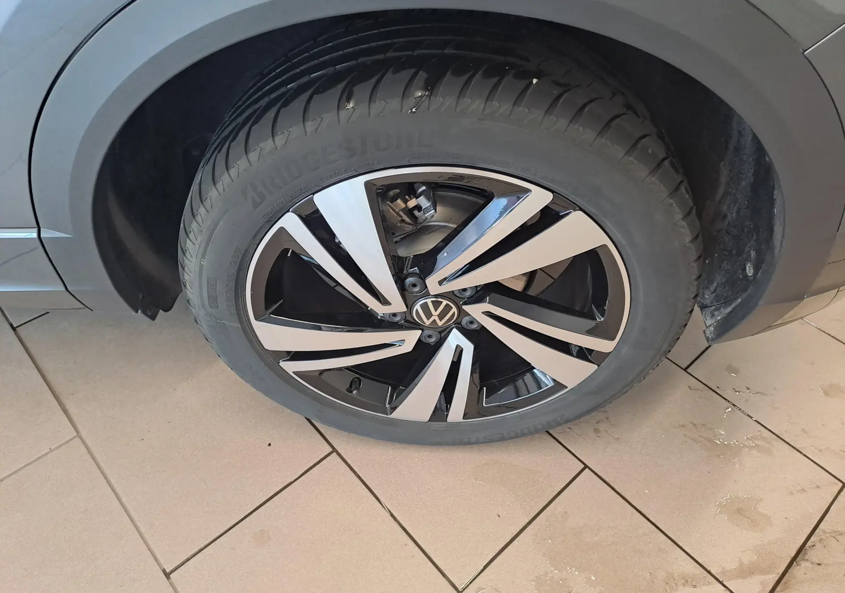 Gros plan sur la roue avant droite du Volkswagen T-Roc 2025 gris Indium avec jante alliage bicolore distinctive.