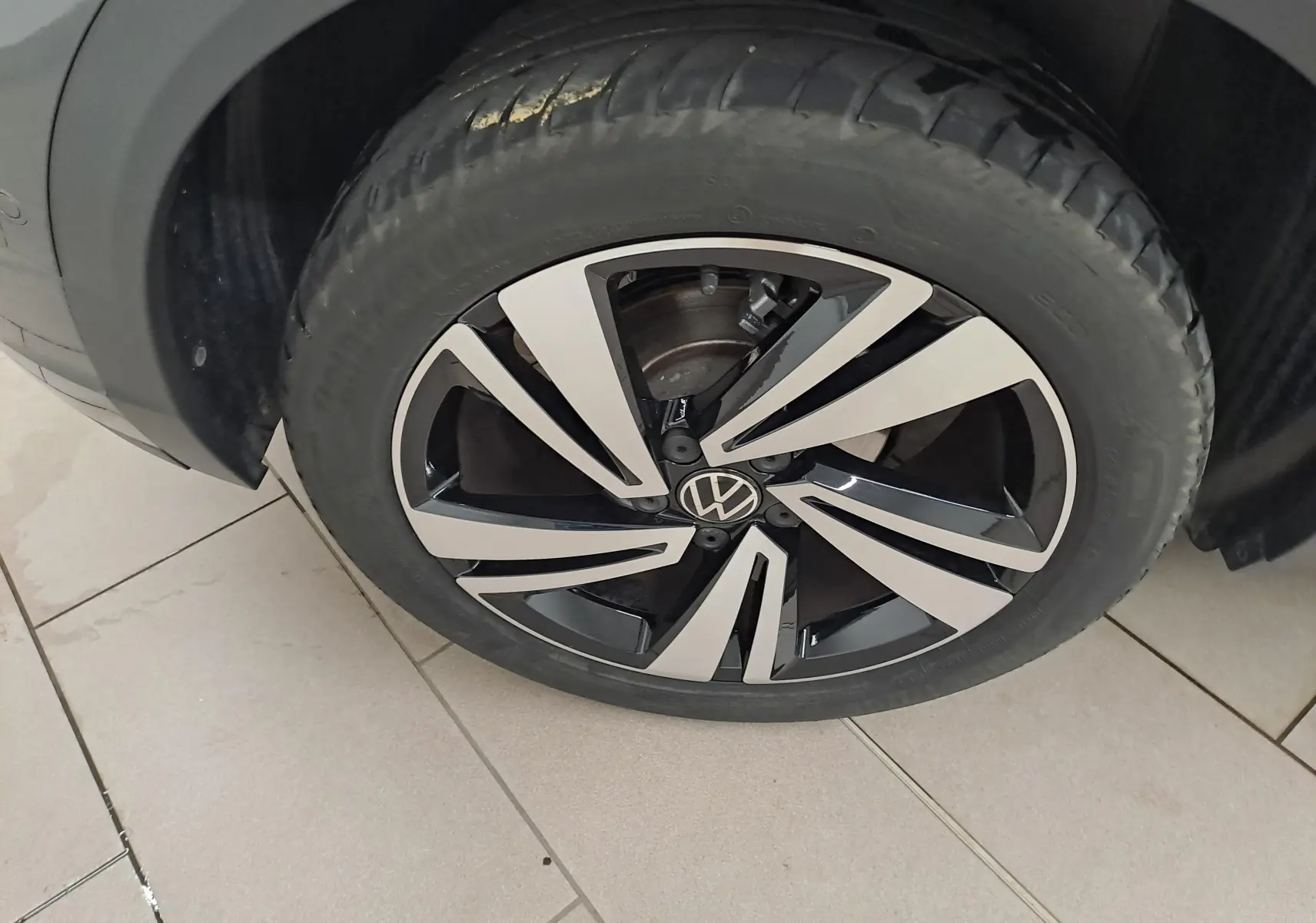 Gros plan sur la roue avant droite du Volkswagen T-Roc 2025, jante alliage bicolore noir et argent avec logo VW au centre.