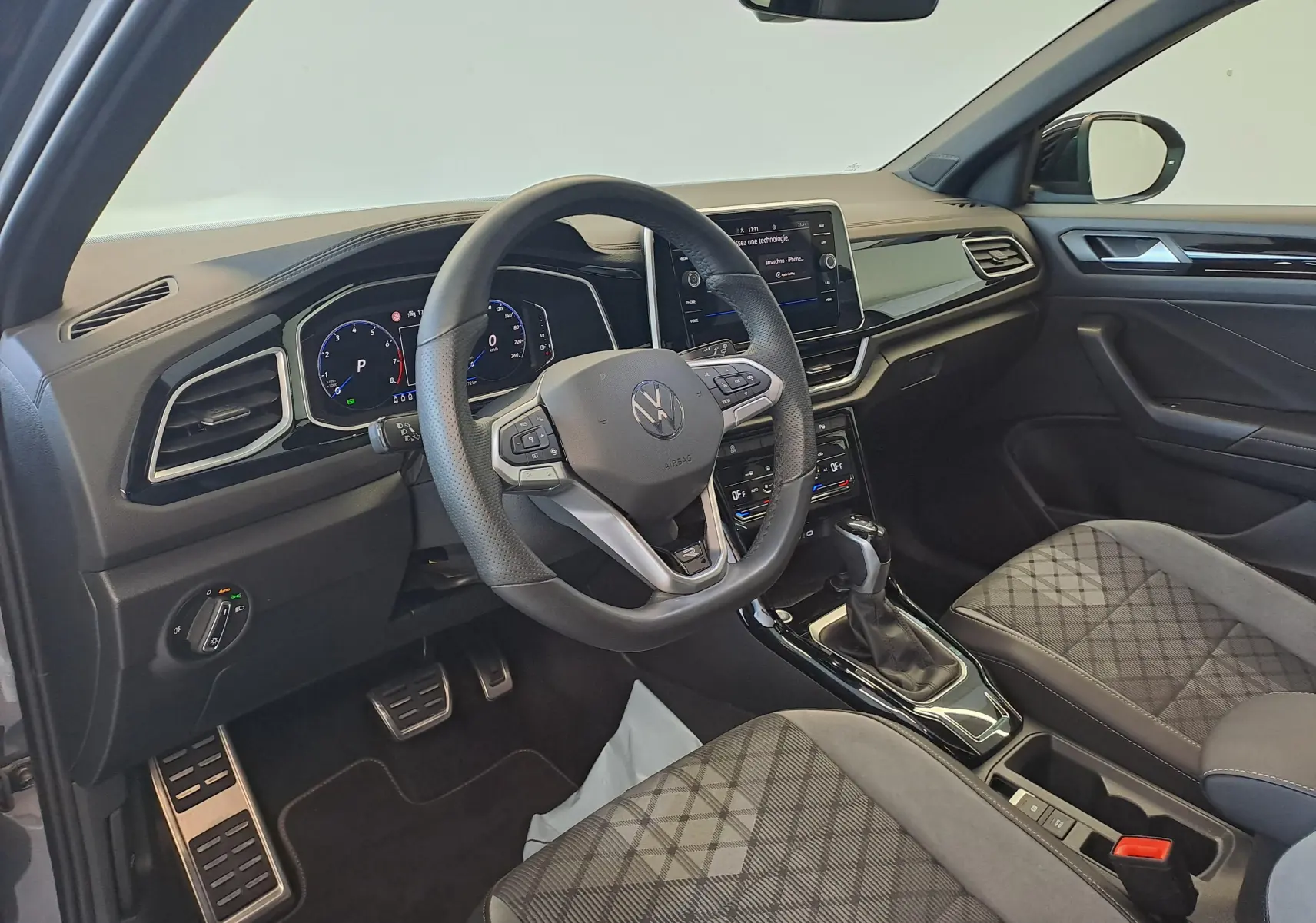 Vue intérieure côté conducteur du Volkswagen T-Roc 2025, volant multifonction et sièges tissu à motifs géométriques.