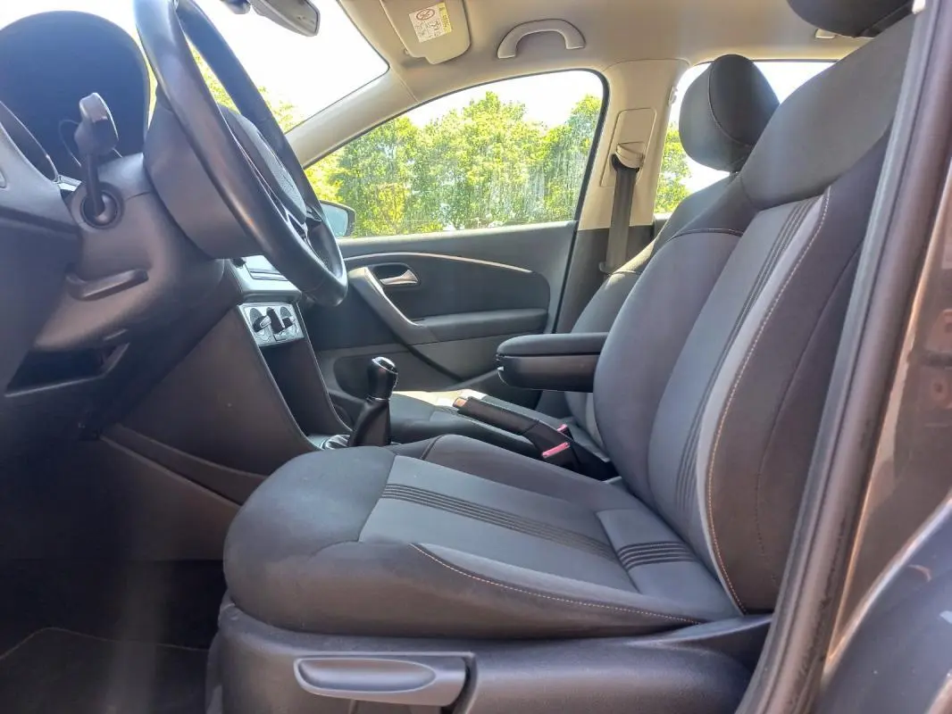 Intérieur avant droit de la Volkswagen Polo gris 2016, montrant les sièges tissu et la boîte manuelle.