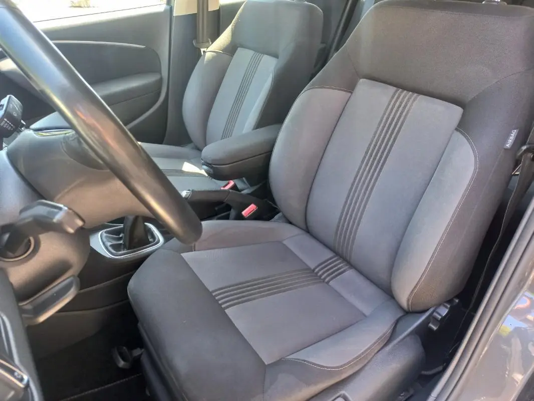 Vue intérieure côté conducteur de la Volkswagen Polo gris 2016, montrant les sièges tissu avec bandes centrales et levier de vitesse manuel.