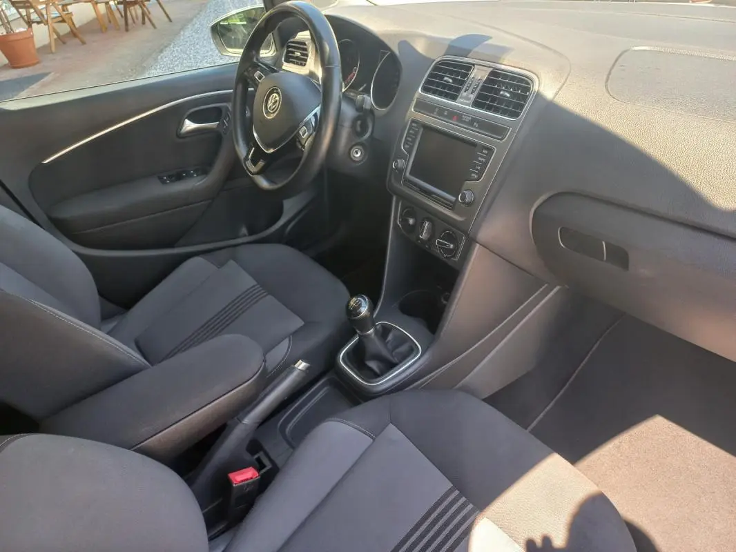 Vue intérieure côté conducteur de la Volkswagen Polo gris 2016, avec volant, tableau de bord et levier de vitesse manuel visibles.
