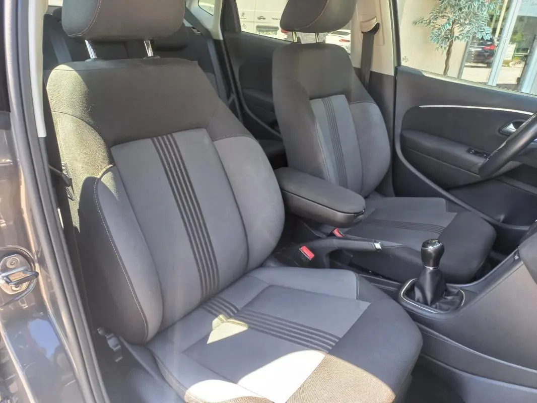 Vue intérieure côté conducteur de la Volkswagen Polo gris 2016, sièges tissu avec bandes centrales et levier de vitesse manuel.