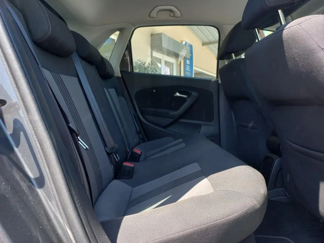 Vue intérieure côté gauche des sièges arrière gris foncé de la Volkswagen Polo 2016 avec ceintures de sécurité visibles.