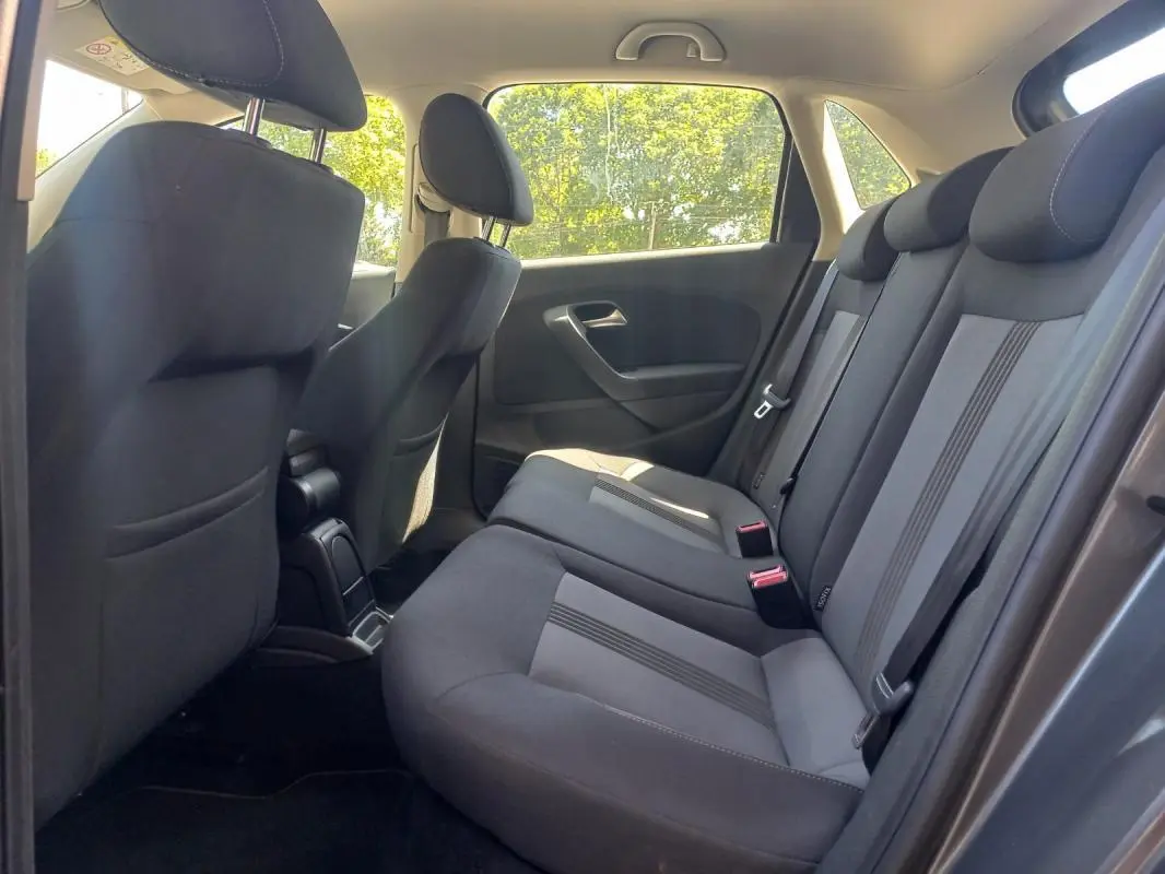 Vue intérieure côté droit des sièges arrière gris foncé de la Volkswagen Polo 2016 avec appuie-têtes et ceintures visibles.