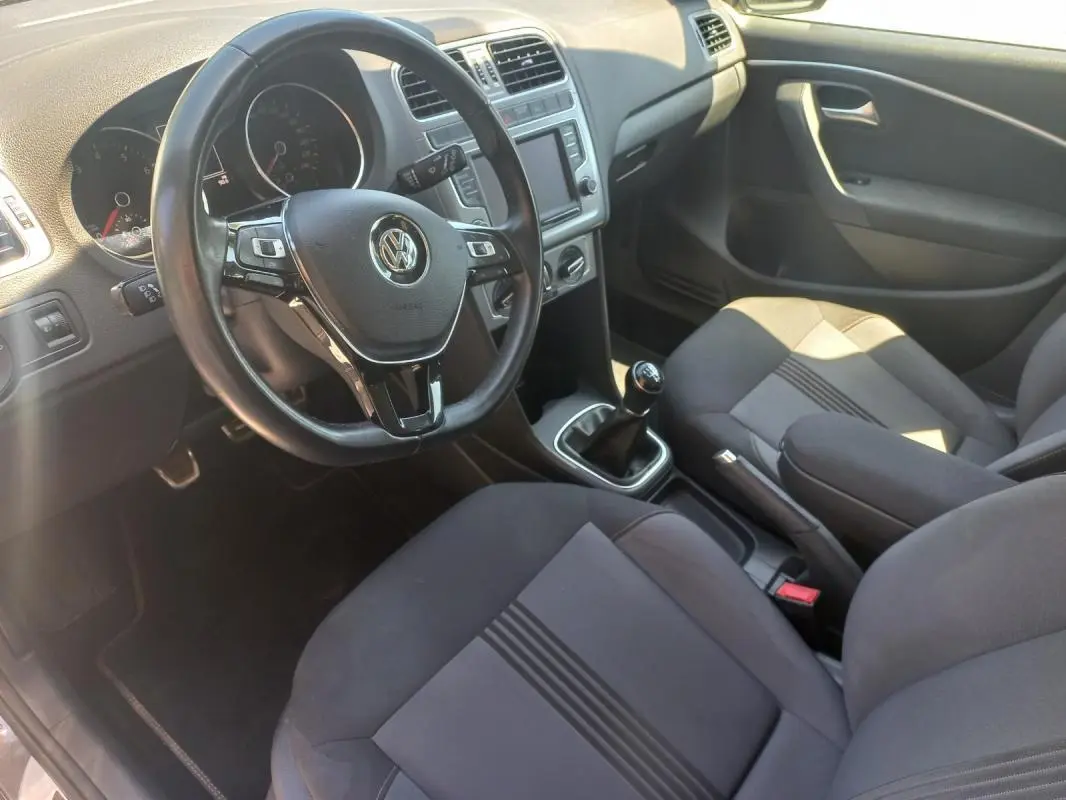 Intérieur de Volkswagen Polo 2016 gris, vue côté conducteur, volant multifonction et levier de vitesse manuel visibles.