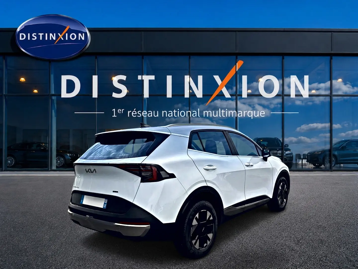 KIA SPORTAGE 1.6 hybride blanc vu en 3/4 arrière droit devant une vitrine Distinxion.