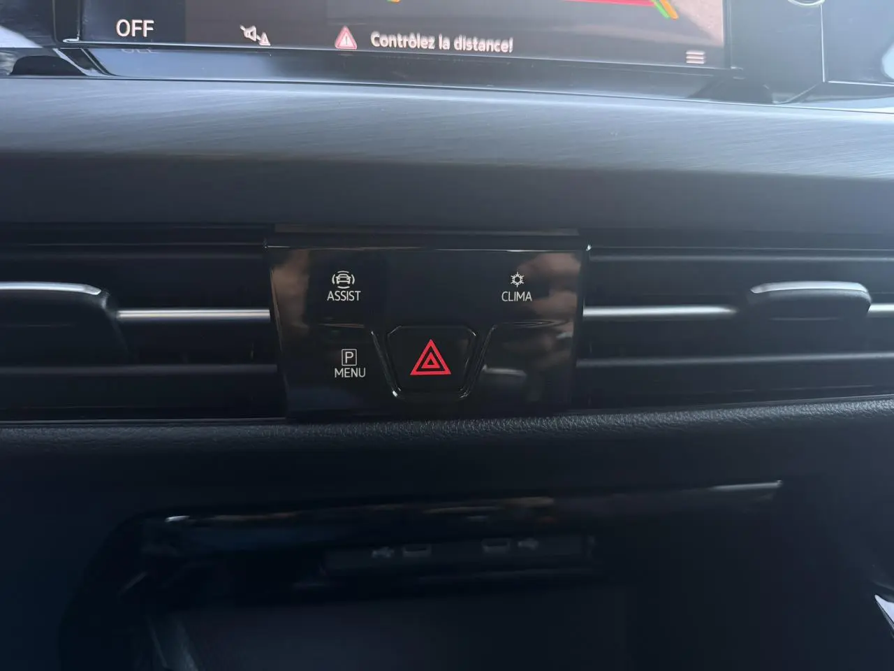 Vue rapprochée du tableau de bord noir de la Volkswagen Golf VIII 2024, avec boutons d'alerte et d'assistance visibles.
