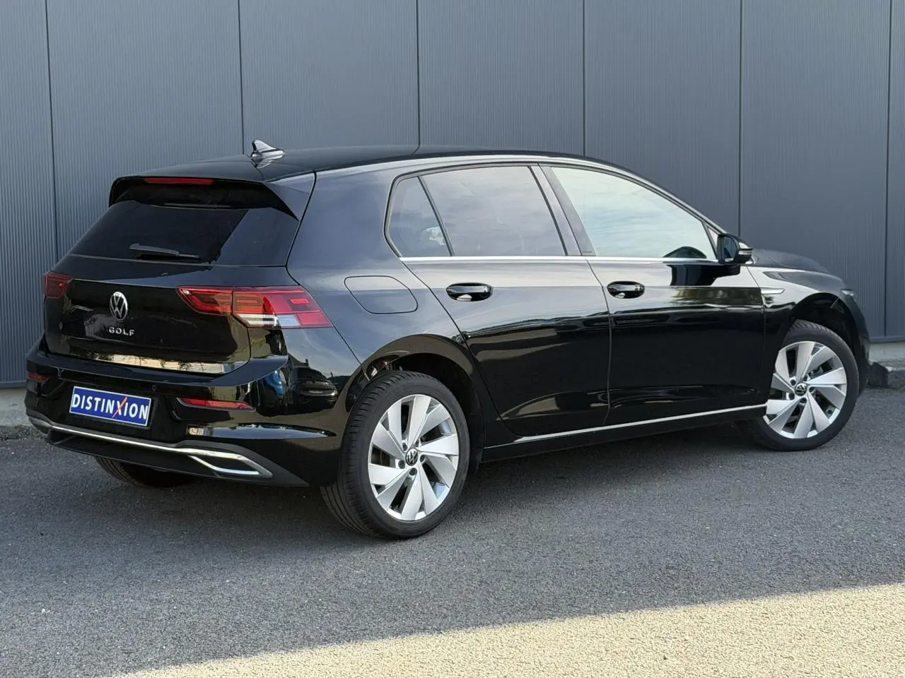Volkswagen Golf VIII noire vue 3/4 arrière droit, avec jantes alliage 17 pouces et baguettes chromées.