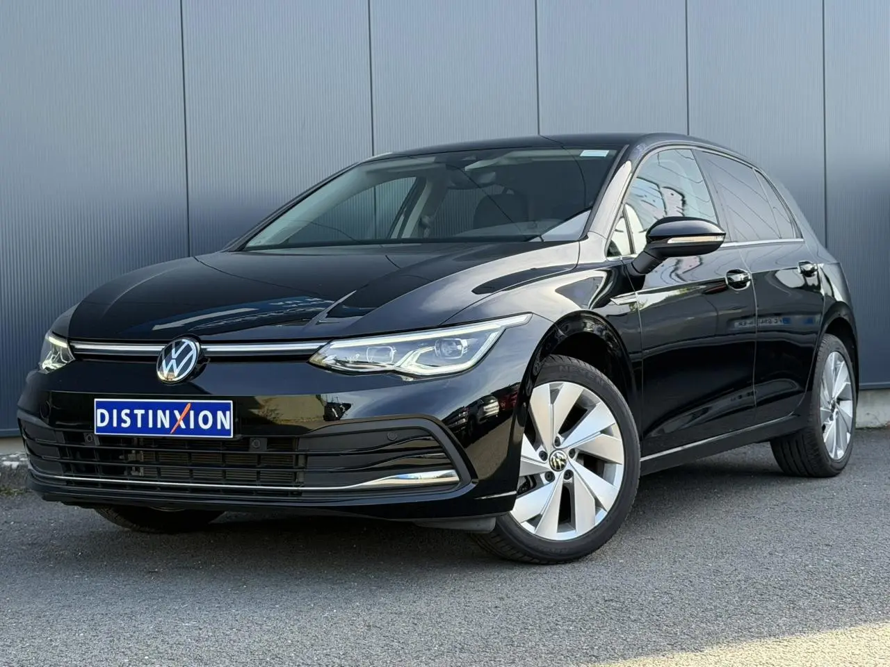 Volkswagen Golf VIII noire vue en 3/4 avant droit, avec jantes alliage et calandre chromée.