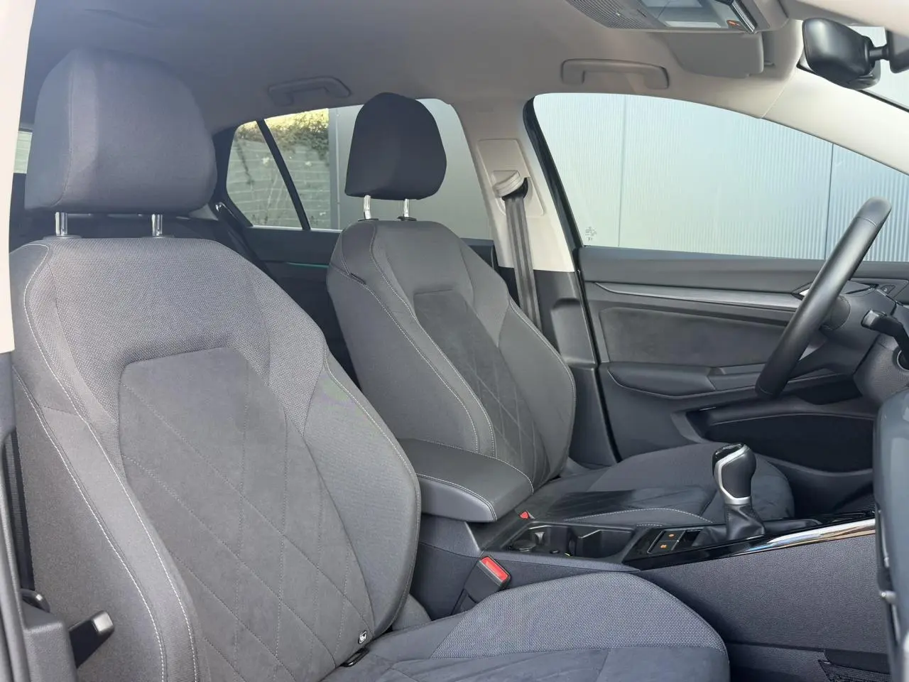 Vue intérieure côté droit de la Volkswagen Golf VIII 1.5 TSI 130 Style 2024, sièges microfleece gris et console centrale.