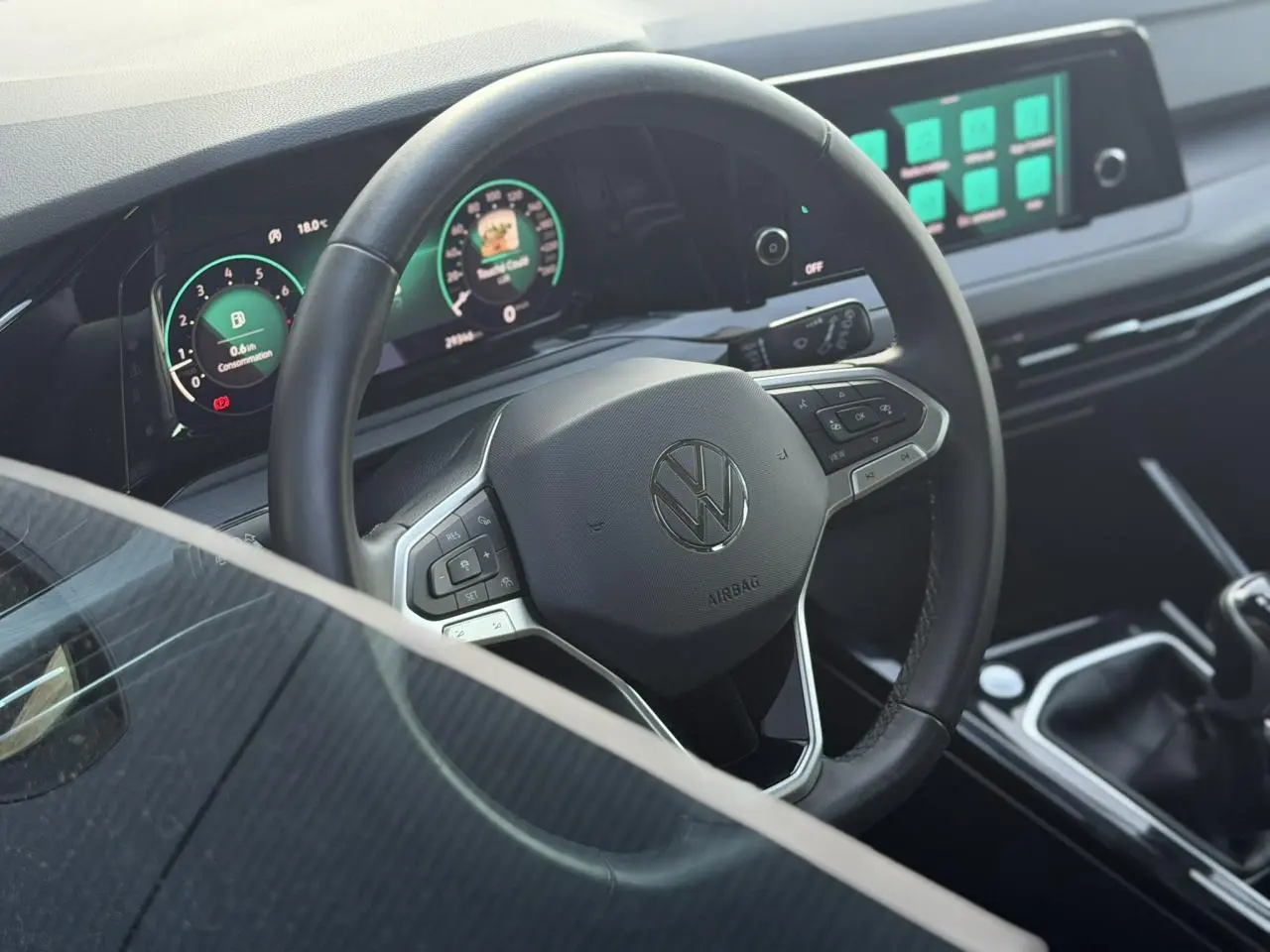 Vue intérieure centrée sur le volant multifonction noir et le tableau de bord digital lumineux d'une Volkswagen Golf VIII 2024.