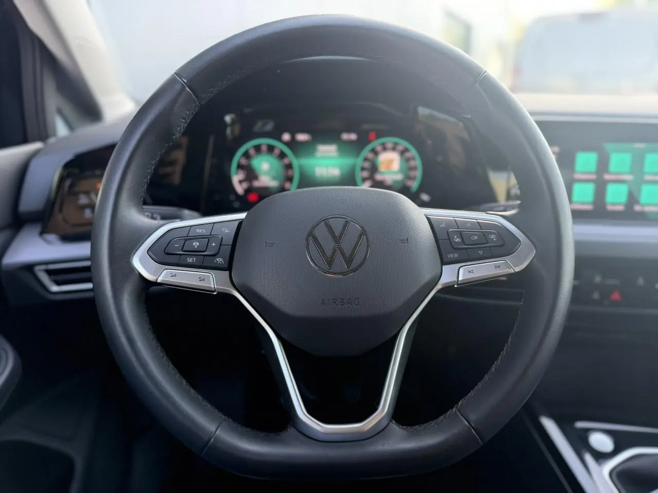 Volant multifonction noir de Volkswagen Golf VIII 2024 avec tableau de bord numérique et écran tactile en arrière-plan.
