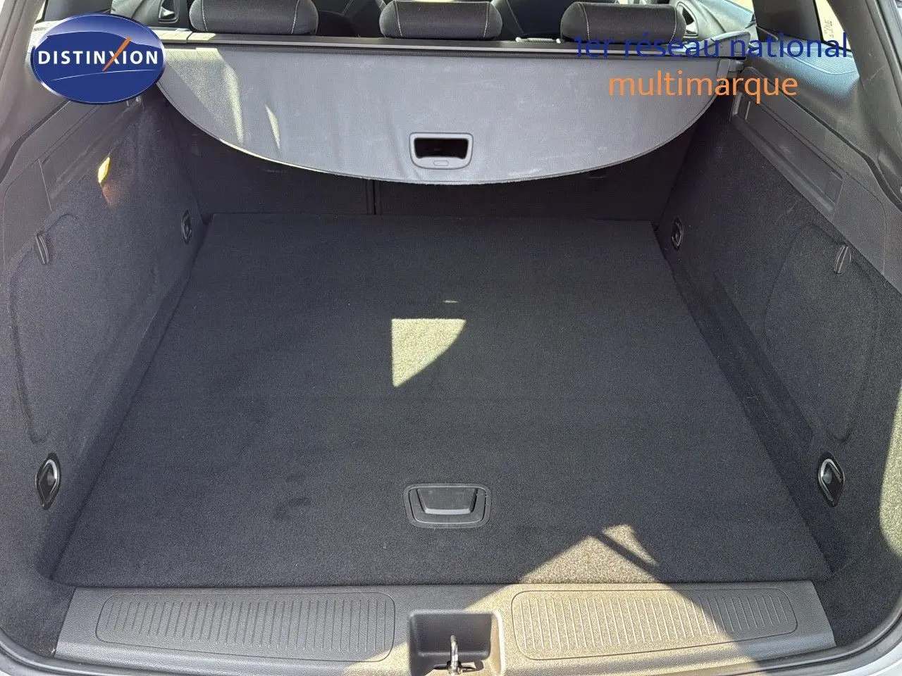 Coffre spacieux et propre de l’Opel Astra Sports Tourer gris minéral métal vu de l’arrière avec cache-bagages déployé.