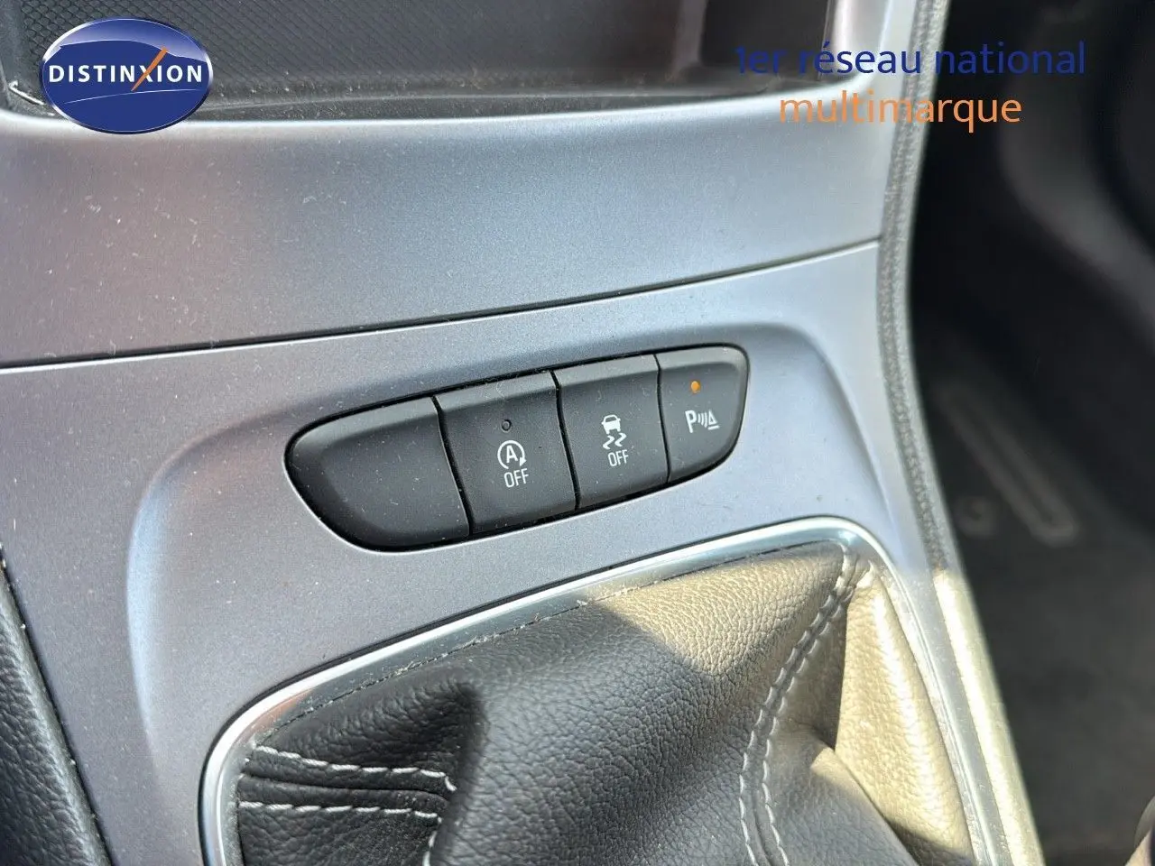 Gros plan sur la console centrale de l'Opel Astra Sports Tourer gris minéral, montrant les boutons de contrôle et le soufflet de levier de vitesse.