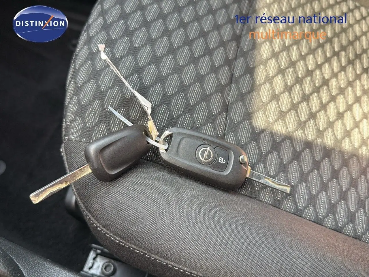 Clé de contact Opel posée sur un siège tissu gris foncé à motifs géométriques dans une Astra Sports Tourer 2021.