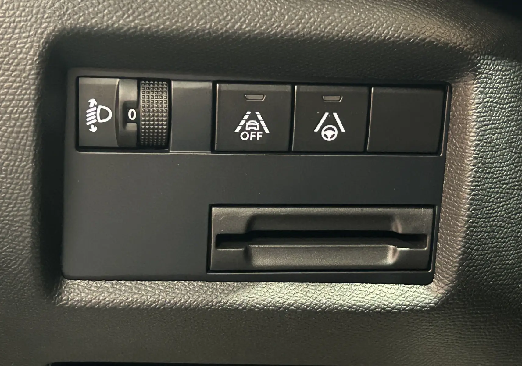 Panneau de commandes intérieures noires avec réglage des phares et boutons d'assistance au conducteur sur Citroën C5 Aircross.