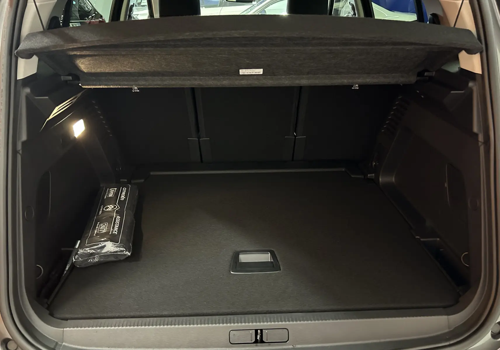 Coffre ouvert du Citroën C5 Aircross gris platinium 2025, montrant un espace de chargement propre avec kit d'assistance visible à gauche.