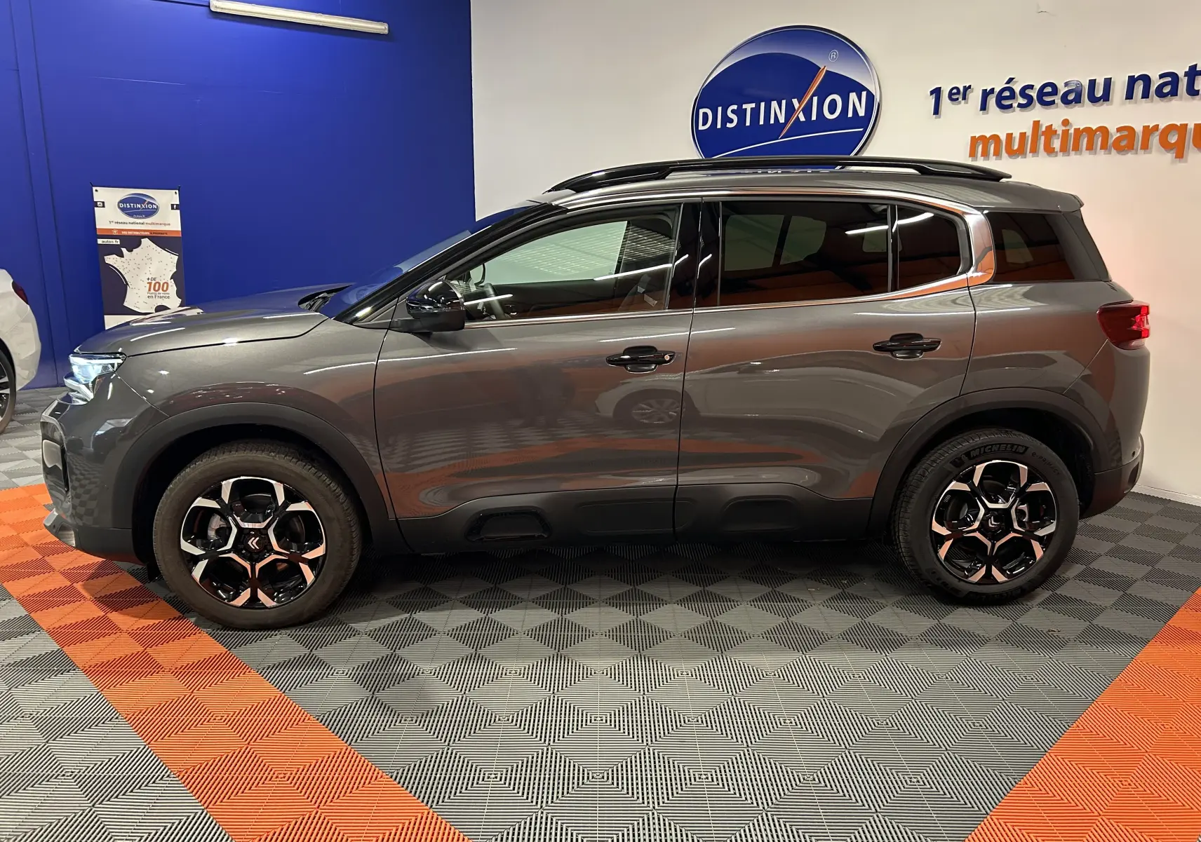 Profil côté gauche d'un Citroën C5 Aircross gris platinium 2025 dans un showroom avec jantes bi-ton.