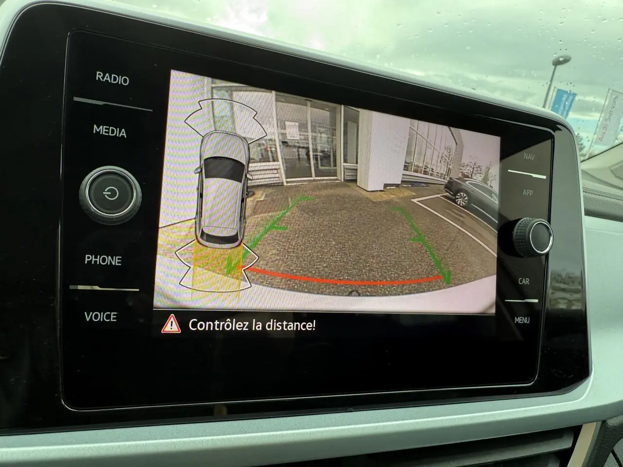 Affichage de la caméra de recul du Volkswagen T-Roc argent pyrite métallisé avec lignes de guidage vertes et rouges sur l'écran central.