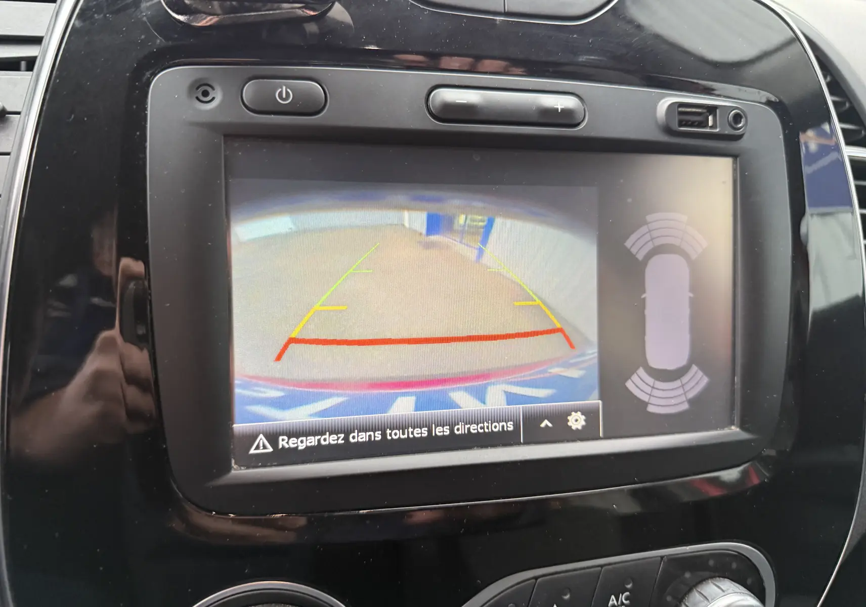 Écran central de la Renault Captur rouge 2017 montrant la caméra de recul avec guidage et capteurs de proximité.