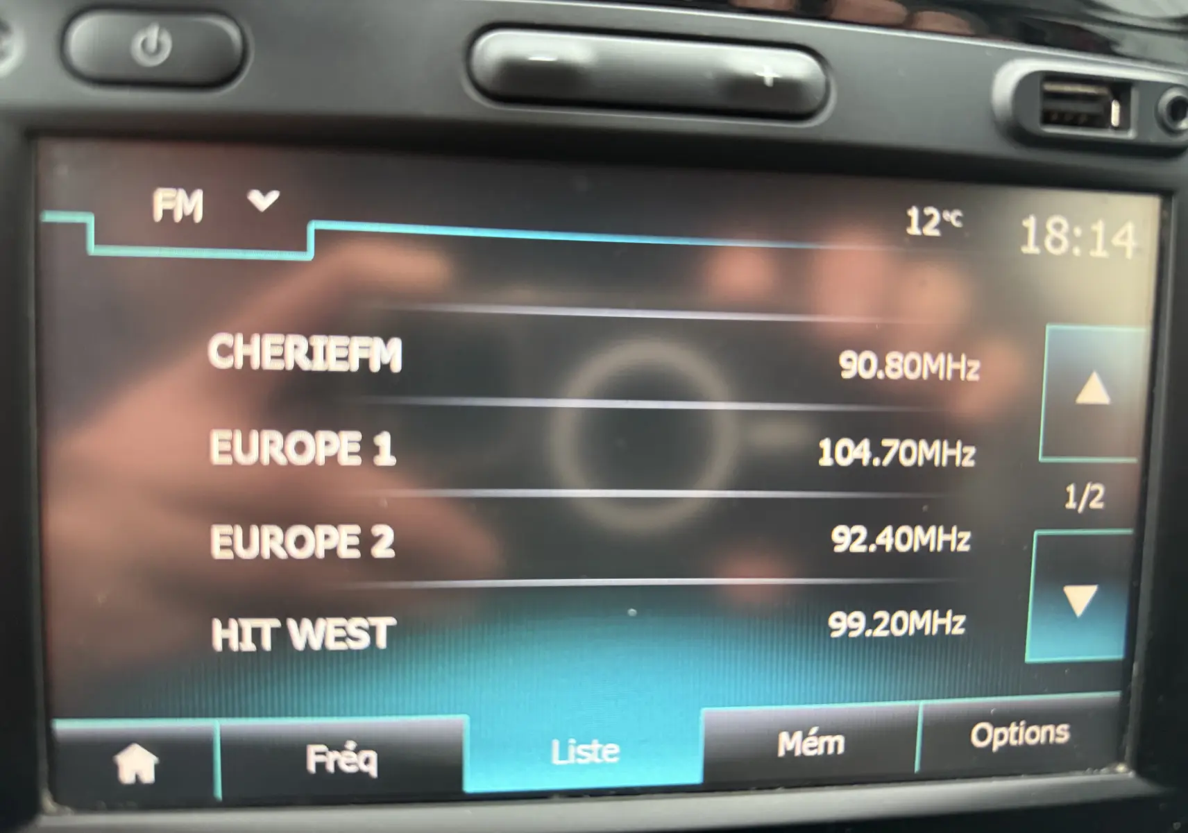 Écran central du système multimédia du Renault Captur rouge, affichant la liste des stations FM avec l'heure et la température.