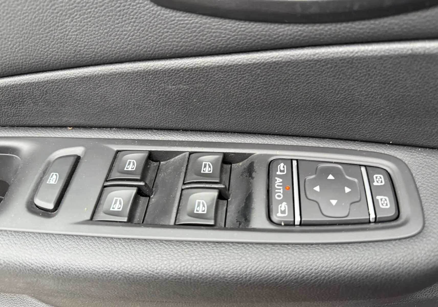 Panneau de commandes des vitres électriques et réglages des rétroviseurs côté conducteur d’un Renault Captur rouge 2017.