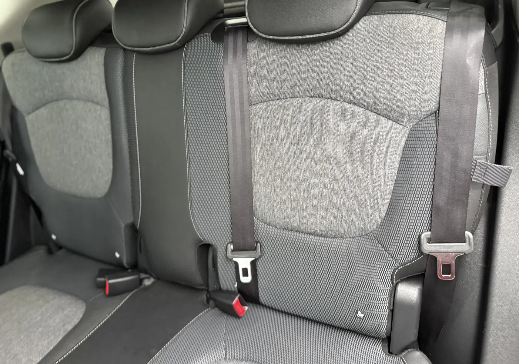 Vue rapprochée des sièges arrière gris et noirs du Renault Captur TCE 120 EDC Intens, avec ceintures de sécurité visibles.