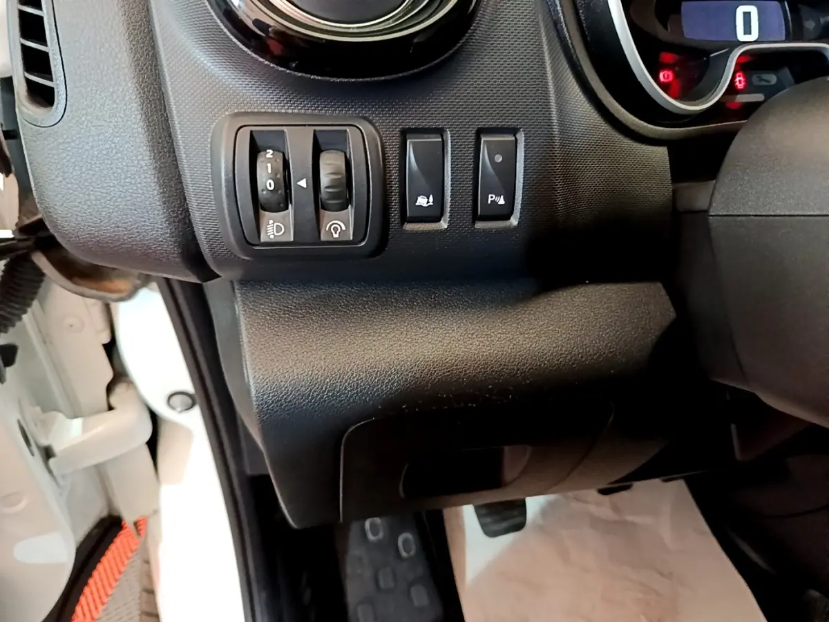 Détail du tableau de bord côté gauche du Renault Trafic Fourgon blanc, avec commandes de réglage des phares et aides à la conduite.