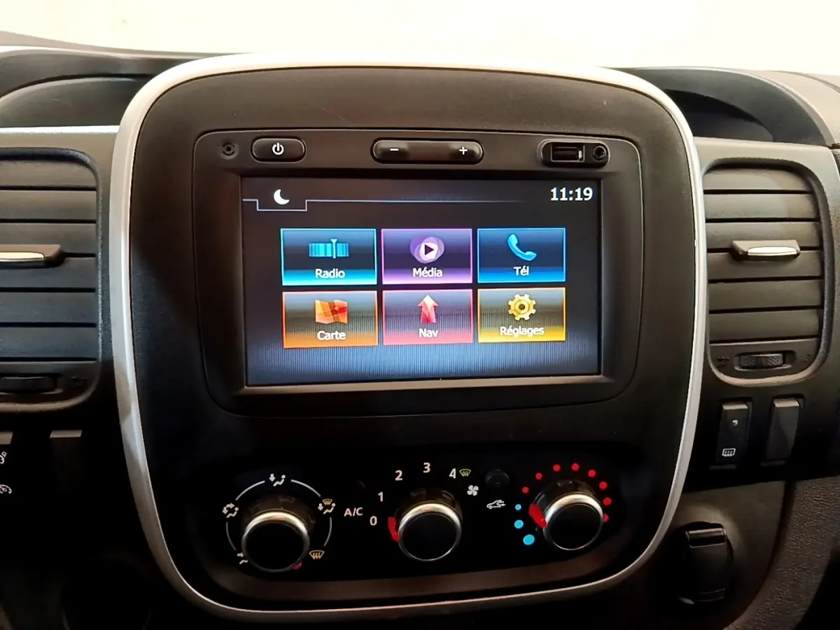 Écran tactile central avec commandes climatisation du Renault Trafic Fourgon blanc, vue intérieure frontale.