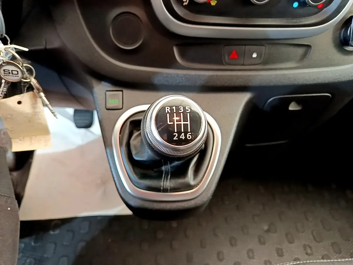 Gros plan sur le levier de vitesses manuel du Renault Trafic Fourgon blanc, avec bouton Eco et tableau de bord partiel.