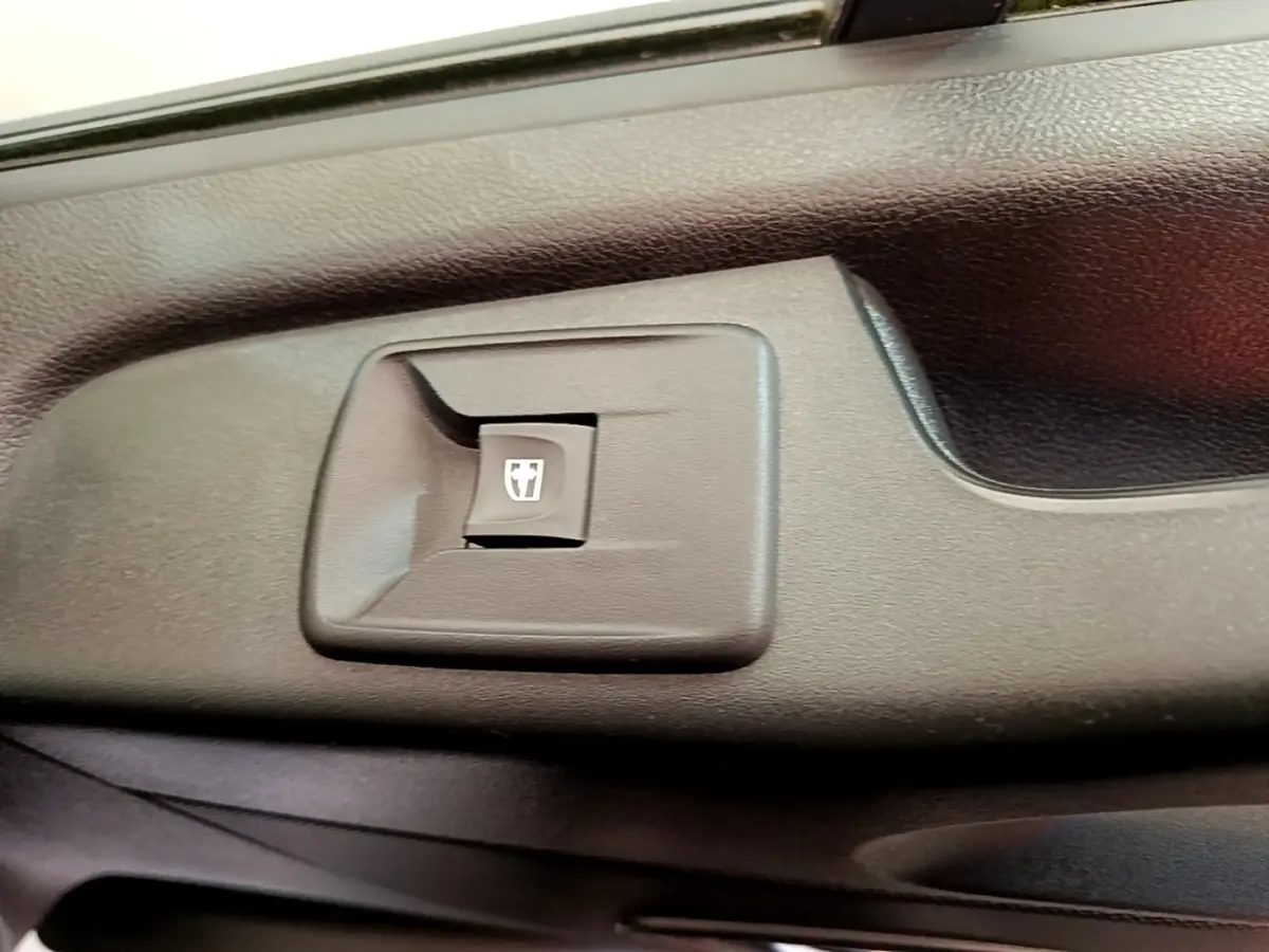 Gros plan sur le bouton de commande de la vitre électrique côté conducteur du Renault Trafic Fourgon blanc.