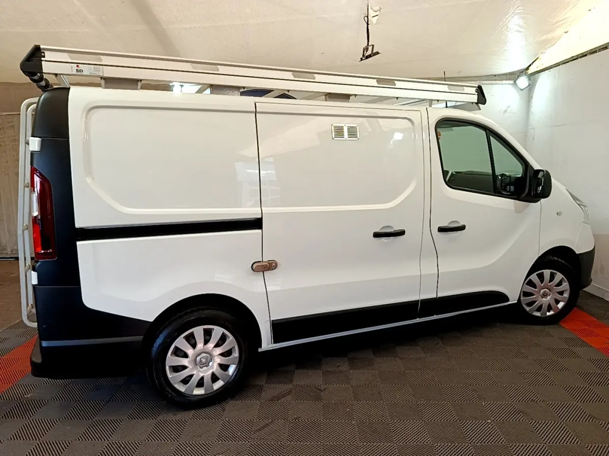 Vue latérale droite d'un Renault Trafic Fourgon blanc L1H1 1200 Confort avec galerie de toit en intérieur.